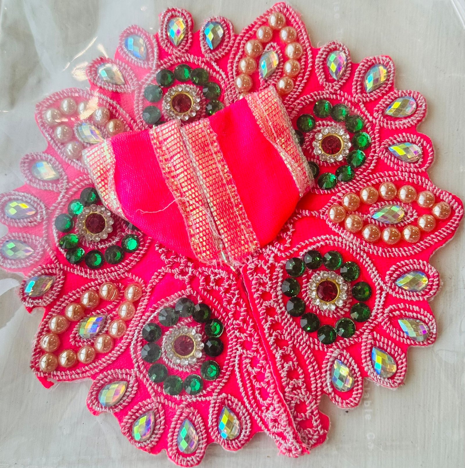 Red Laddu Gopal dress with green stone circles, golden pearls, and shimmering mirror embroidery