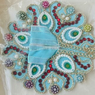 Sky blue Laddu Gopal dress with pearl-lined paisley design, red stones, and multicolor bead accents