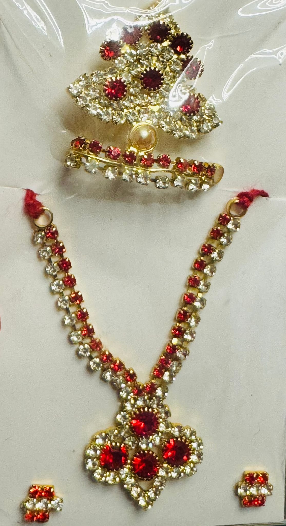 Laddu Gopal accessory set with red and white stones, gold-tone floral mukut, necklace, and matching earrings