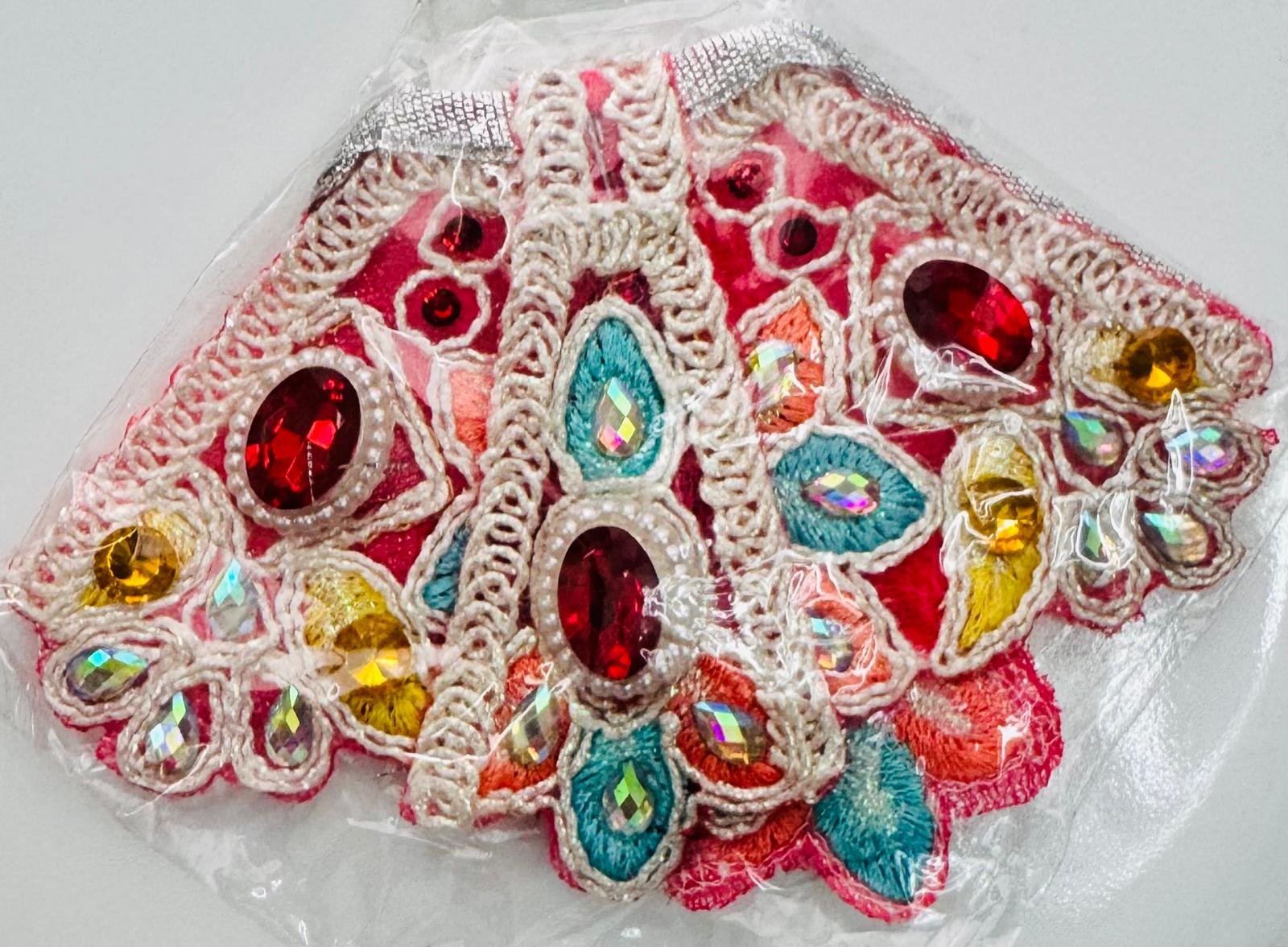 Multicolored Radha Rani dress with intricate floral embroidery, red and yellow gemstones, and crystal embellishments, wrapped in clear plastic.