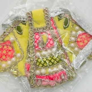 Yellow Radha Rani dress with pink and green floral embroidery, pearl decorations, and silver lace, sealed in transparent packaging.